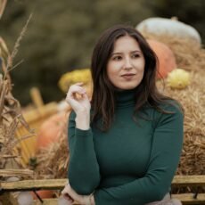 a woman standing in front of a pile of hay