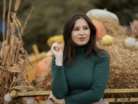 a woman standing in front of a pile of hay