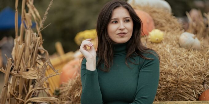 a woman standing in front of a pile of hay